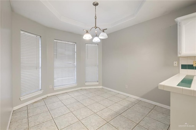 unfurnished dining area with baseboards and a tray ceiling