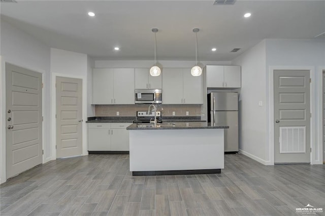 1520 New Orleans Cir, Pharr, TX 78577 - kitchen with decorative backsplash, a kitchen island with sink, baseboards, white cabinets, and stainless steel appliances