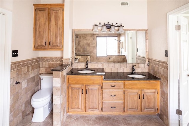 bathroom featuring tile patterned floors, vanity, tile walls, and toilet