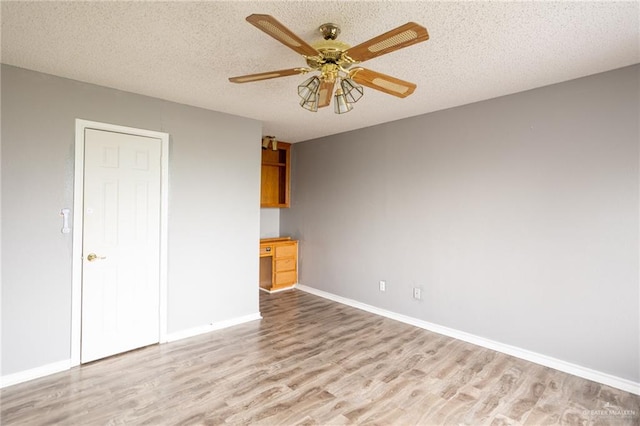 spare room with a textured ceiling, light hardwood / wood-style flooring, and ceiling fan