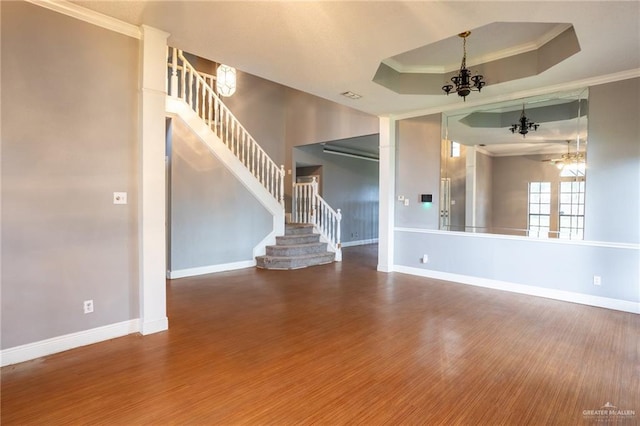 unfurnished living room with wood-type flooring, a tray ceiling, an inviting chandelier, and crown molding