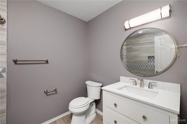 full bath with baseboards, toilet, vanity, wood finished floors, and a textured ceiling