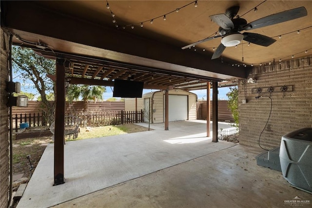 view of patio / terrace with a ceiling fan, an outdoor structure, and fence