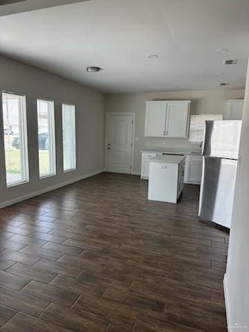 kitchen with white cabinets, dark hardwood / wood-style floors, a kitchen island, and stainless steel refrigerator