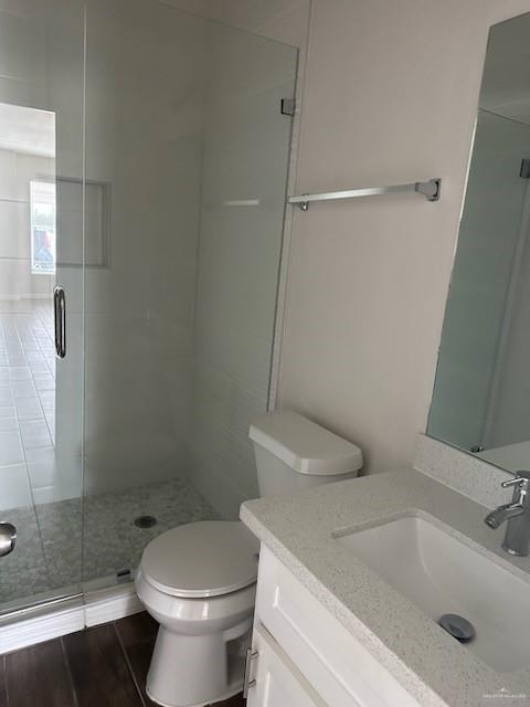 bathroom with hardwood / wood-style floors, vanity, a shower with shower door, and toilet