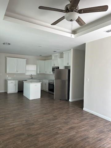 kitchen featuring white cabinets, stainless steel appliances, a kitchen island, and dark wood-type flooring