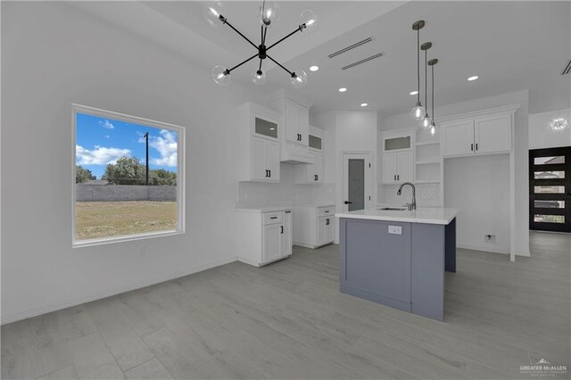 kitchen featuring white cabinetry, a center island with sink, an inviting chandelier, and sink