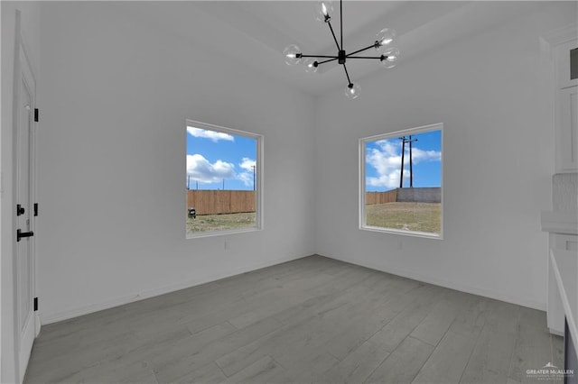 unfurnished living room with a chandelier, light hardwood / wood-style floors, and a healthy amount of sunlight