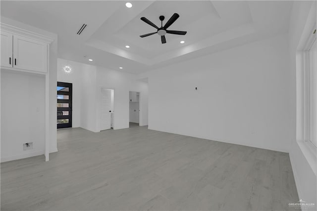 empty room featuring a tray ceiling, light hardwood / wood-style flooring, and ceiling fan