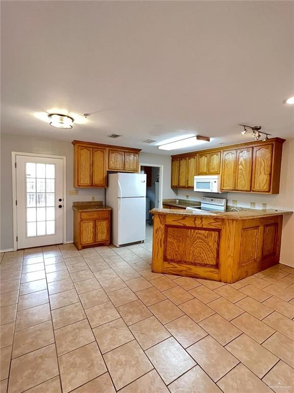 kitchen with kitchen peninsula, light tile patterned flooring, and white appliances