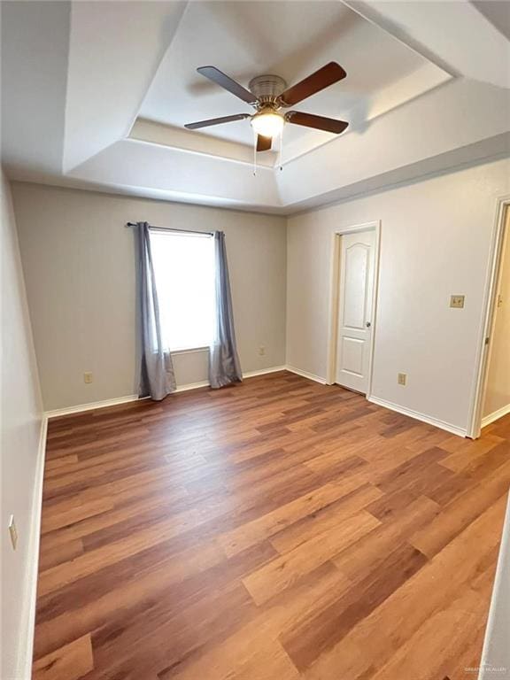 spare room with hardwood / wood-style flooring, ceiling fan, and a raised ceiling