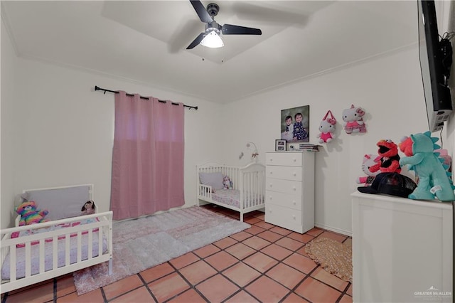 tiled bedroom featuring ceiling fan and a nursery area