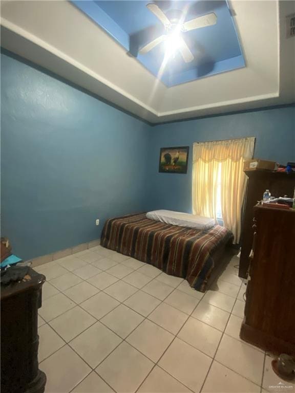 bedroom featuring ceiling fan, a raised ceiling, and light tile patterned floors