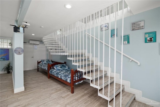 bedroom featuring hardwood / wood-style flooring and an AC wall unit