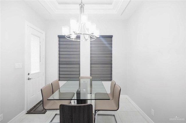 tiled dining area with a raised ceiling and a chandelier