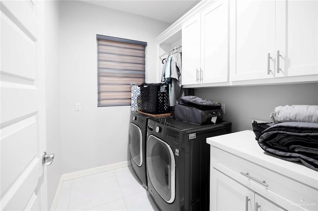 clothes washing area featuring cabinets, light tile patterned floors, and washer and clothes dryer