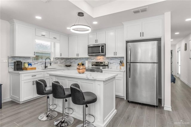 kitchen featuring white cabinetry, sink, hanging light fixtures, a center island, and stainless steel appliances