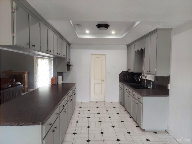 kitchen featuring gray cabinets, a raised ceiling, and sink