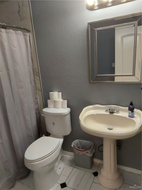 115 Breyfogle Rd, Palmview, TX 78572 - bathroom with toilet, marble look tile flooring, baseboards, and a shower with curtain
