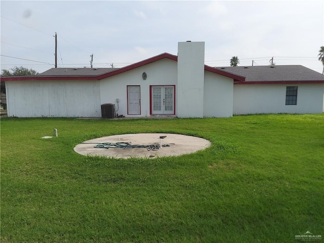 rear view of property with a lawn, french doors, and central AC