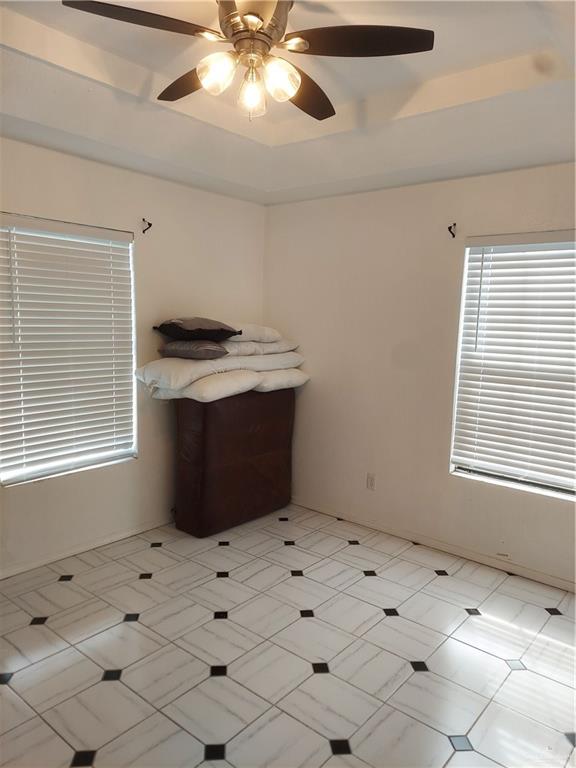 empty room with a raised ceiling and ceiling fan