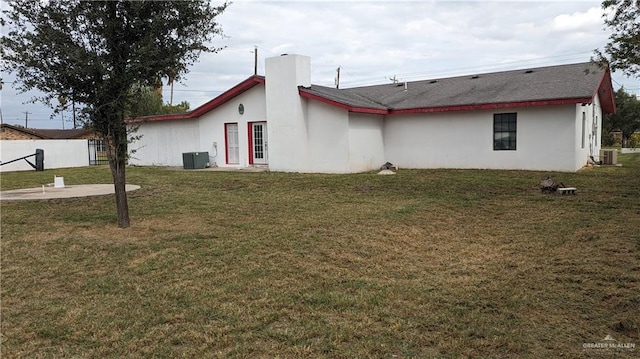 rear view of house with central AC and a yard