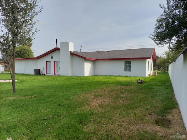 rear view of house with a yard and central AC