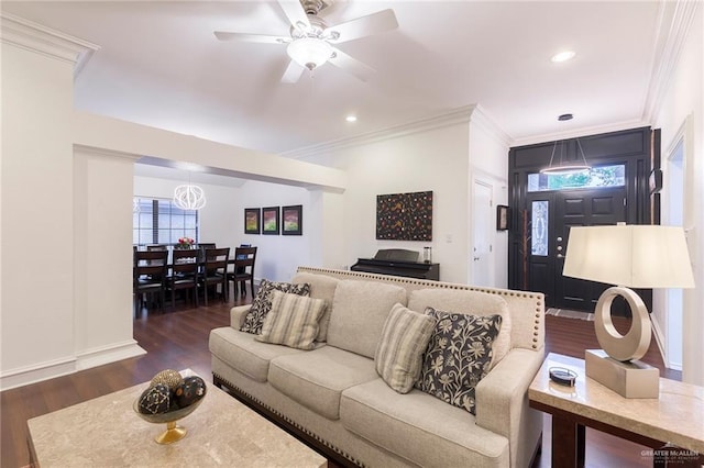 living room with ceiling fan with notable chandelier, crown molding, and dark wood-type flooring