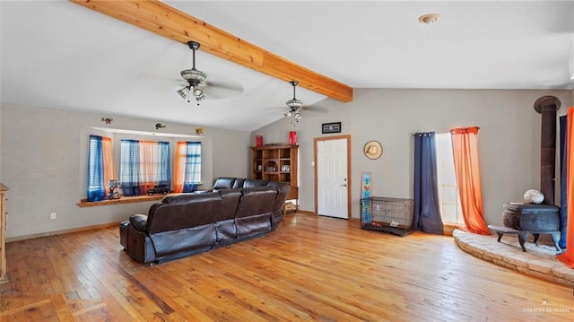 living room with ceiling fan, lofted ceiling with beams, light wood-type flooring, and a wood stove