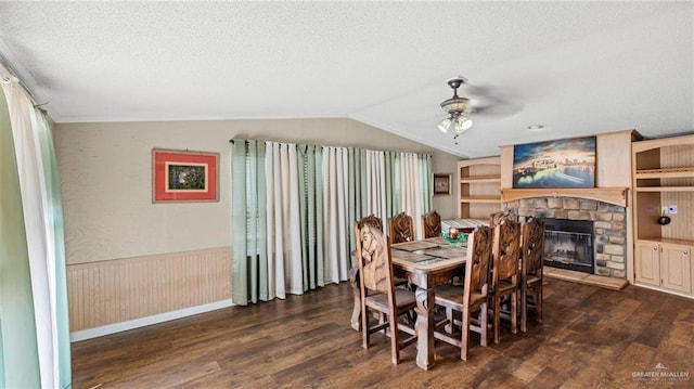 dining space with a textured ceiling, ceiling fan, dark hardwood / wood-style flooring, and a fireplace