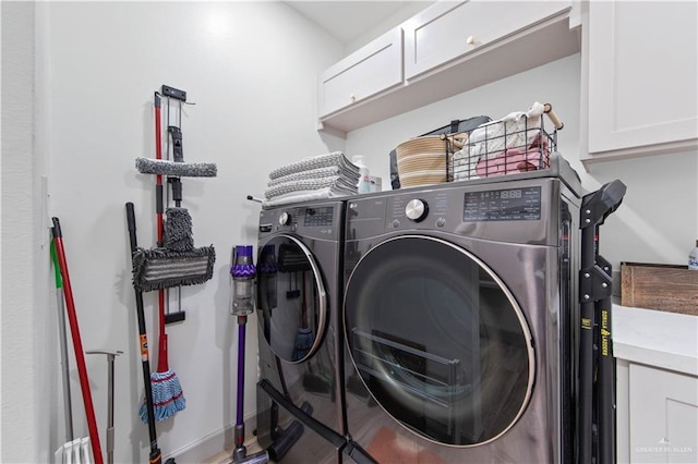 laundry room featuring baseboards, cabinet space, and washer and clothes dryer