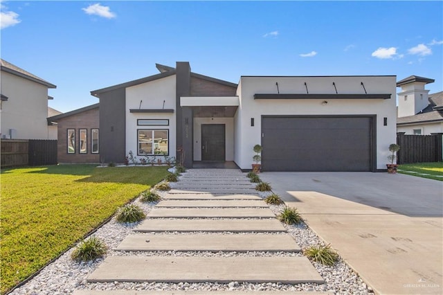contemporary home with fence, an attached garage, a front yard, and concrete driveway