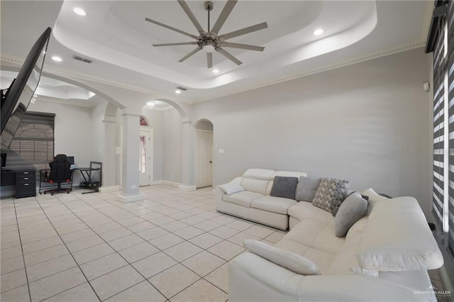 living room with a raised ceiling, ceiling fan, decorative columns, and light tile patterned flooring