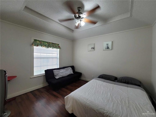 bedroom featuring a textured ceiling, a raised ceiling, baseboards, and wood finished floors