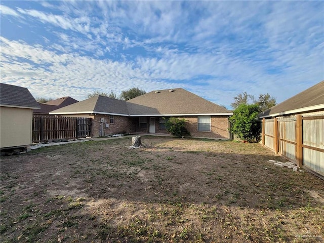 back of property featuring an outbuilding, brick siding, and a fenced backyard