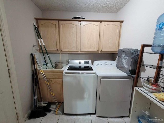 laundry area with light tile patterned flooring, cabinet space, a textured ceiling, and separate washer and dryer