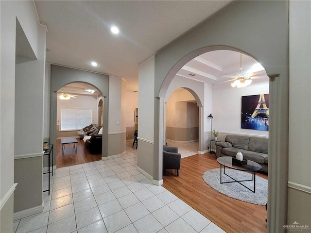 hall with recessed lighting, baseboards, arched walkways, and light wood-style flooring