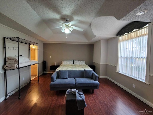 bedroom featuring a textured ceiling, dark wood-type flooring, and a tray ceiling