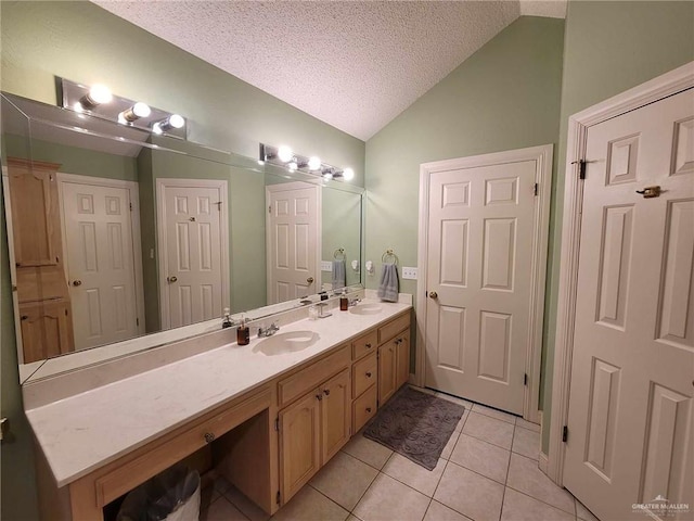 full bath featuring double vanity, a sink, vaulted ceiling, a textured ceiling, and tile patterned floors