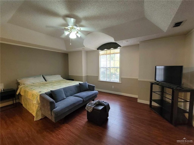 bedroom featuring visible vents, baseboards, wood finished floors, a textured ceiling, and a raised ceiling