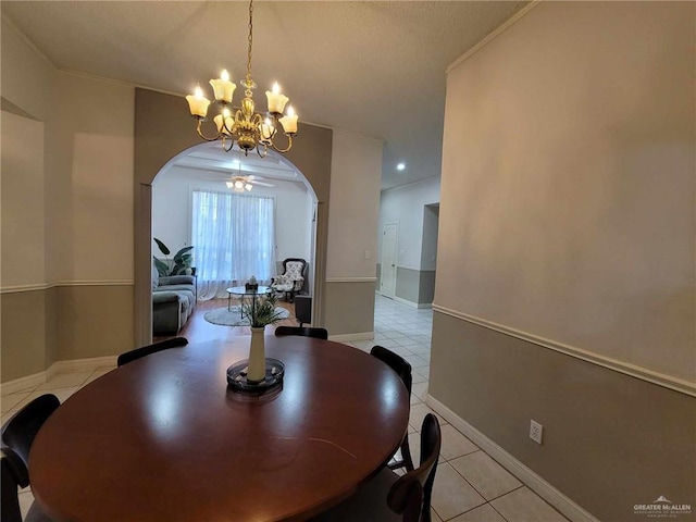 dining space featuring baseboards, light tile patterned flooring, arched walkways, ornamental molding, and a notable chandelier