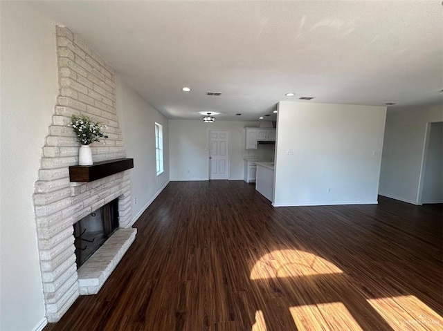 unfurnished living room featuring dark wood finished floors, baseboards, visible vents, recessed lighting, and a fireplace