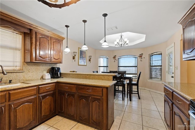 kitchen featuring a notable chandelier, decorative backsplash, sink, hanging light fixtures, and light tile patterned floors