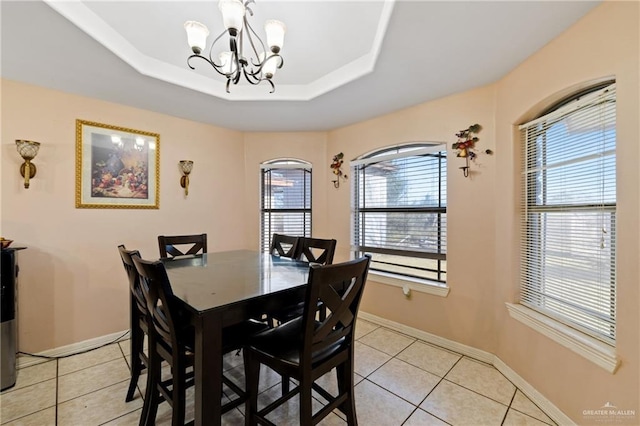 tiled dining room featuring an inviting chandelier and a tray ceiling