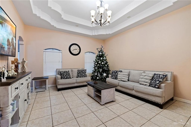 tiled living room featuring a raised ceiling and a notable chandelier