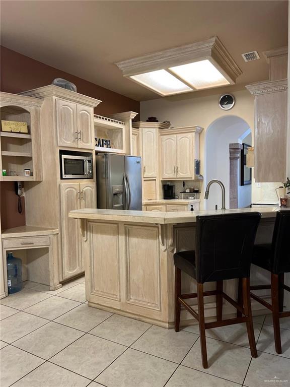 kitchen featuring a breakfast bar, appliances with stainless steel finishes, kitchen peninsula, and light tile patterned floors