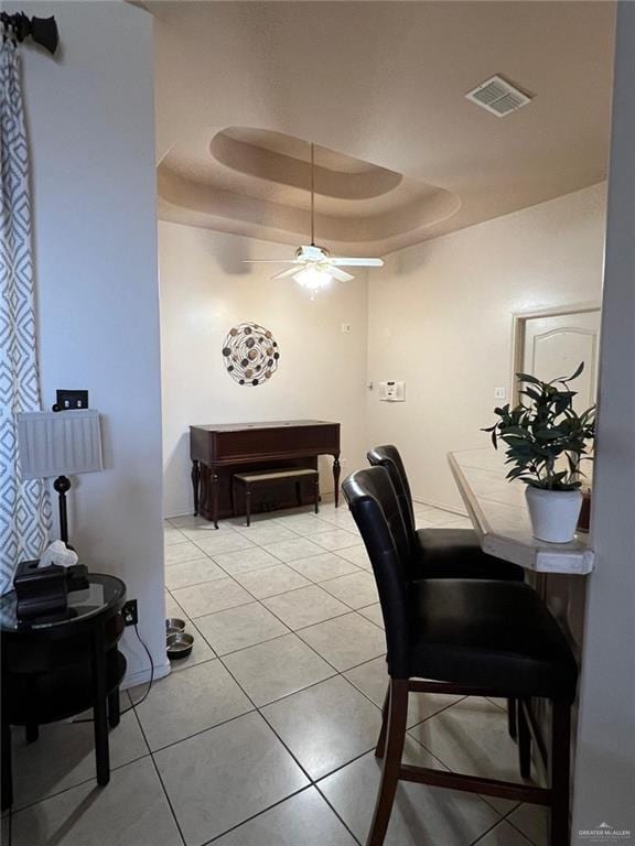 interior space with a tray ceiling, ceiling fan, and light tile patterned flooring