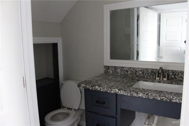 bathroom featuring vanity, toilet, and vaulted ceiling