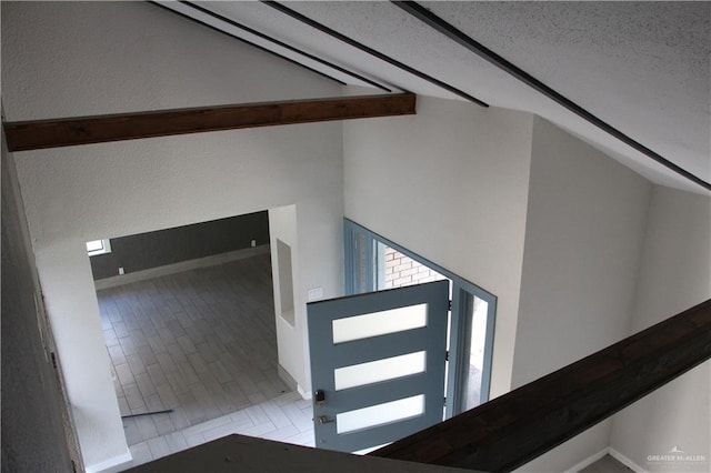 staircase featuring tile patterned flooring, beam ceiling, a textured ceiling, and high vaulted ceiling