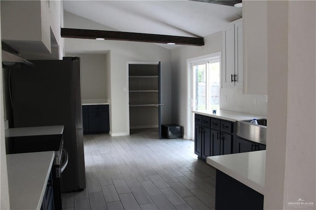 kitchen with vaulted ceiling with beams, white cabinetry, gray cabinetry, and black fridge